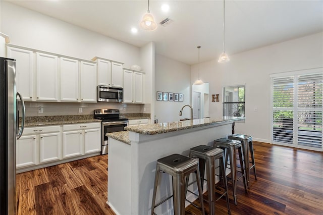 kitchen featuring stainless steel appliances, dark wood-style flooring, white cabinetry, and tasteful backsplash