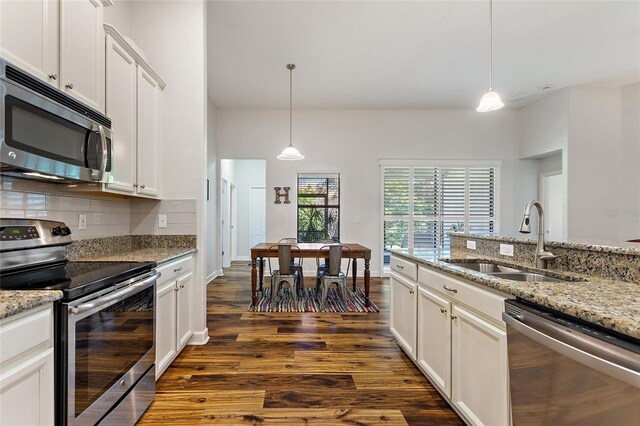 kitchen featuring a sink, appliances with stainless steel finishes, backsplash, dark wood finished floors, and pendant lighting