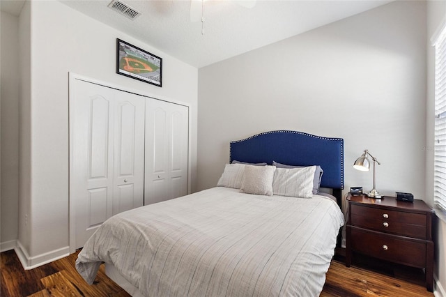 bedroom with wood finished floors, visible vents, baseboards, a ceiling fan, and a closet