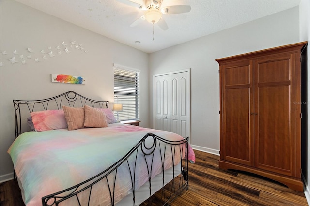 bedroom with dark wood-style floors, ceiling fan, a closet, and baseboards