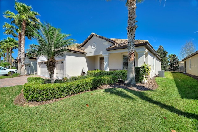 mediterranean / spanish-style home with decorative driveway, a tile roof, stucco siding, a garage, and a front lawn