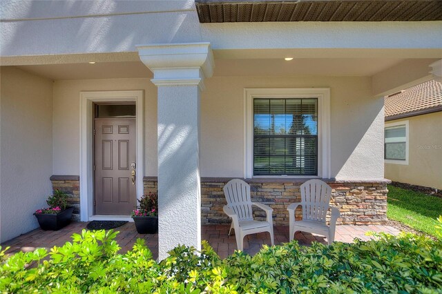 doorway to property with stone siding and stucco siding