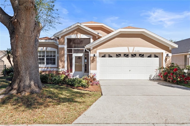 view of front of home with concrete driveway, an attached garage, and stucco siding