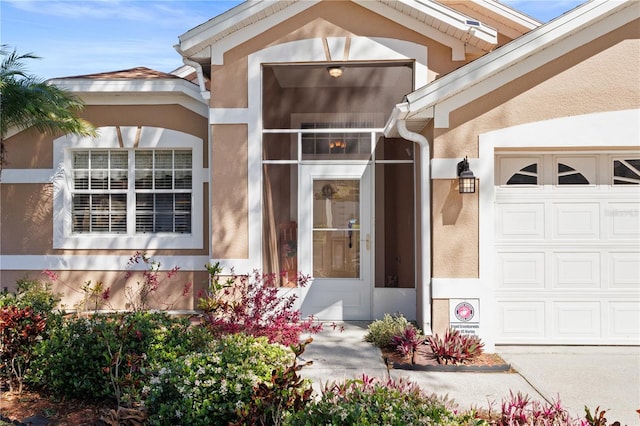 entrance to property with an attached garage and stucco siding