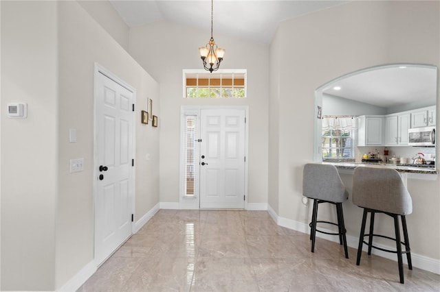 entryway featuring baseboards, arched walkways, lofted ceiling, marble finish floor, and an inviting chandelier