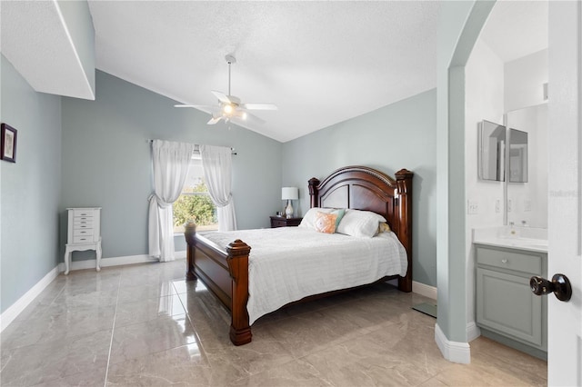 bedroom featuring lofted ceiling, ceiling fan, ensuite bath, and baseboards