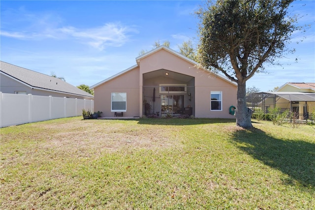 back of house featuring a yard, fence, and stucco siding