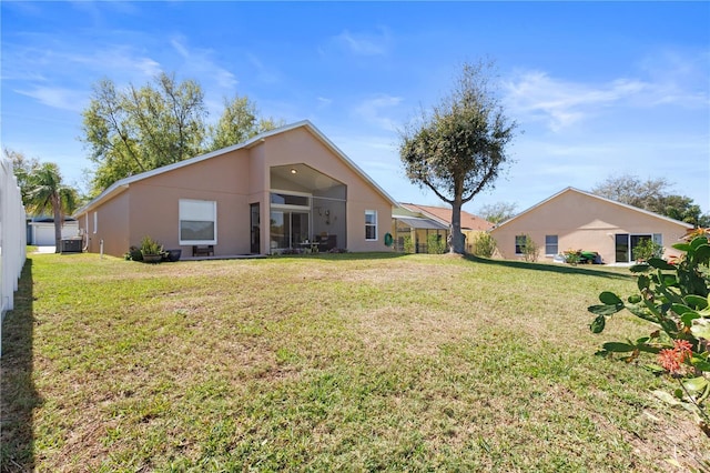 back of property with stucco siding, a yard, and central air condition unit