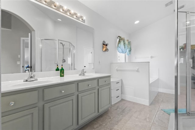 bathroom featuring a garden tub, double vanity, a stall shower, and a sink