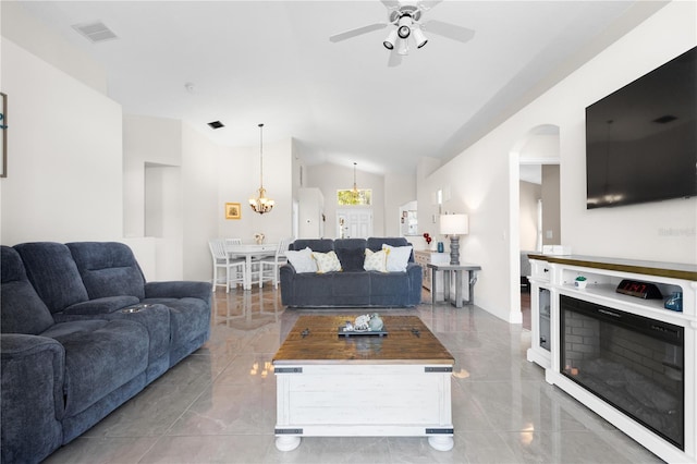 living room featuring marble finish floor, a fireplace, visible vents, vaulted ceiling, and ceiling fan with notable chandelier