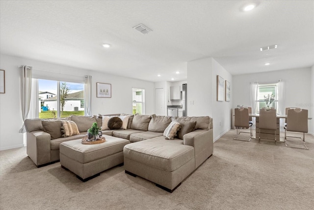 living area with light carpet, baseboards, visible vents, and recessed lighting