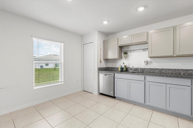 kitchen with light tile patterned floors, baseboards, gray cabinetry, stainless steel dishwasher, and a sink