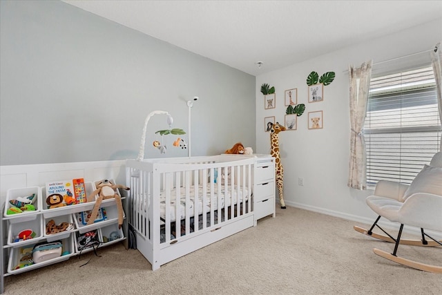 carpeted bedroom with a crib and baseboards