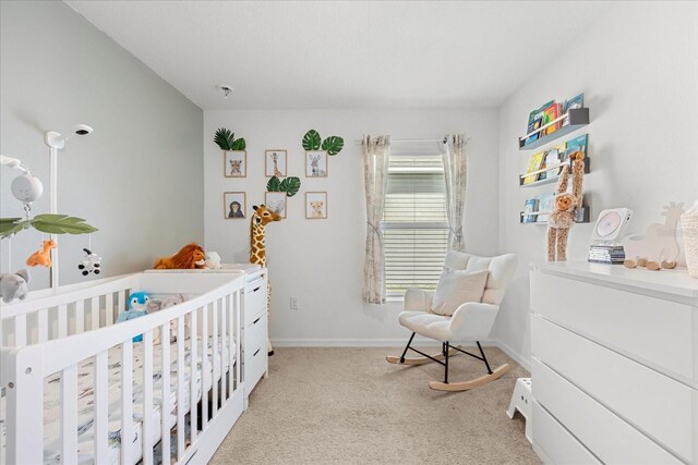 bedroom with light carpet, a crib, and baseboards