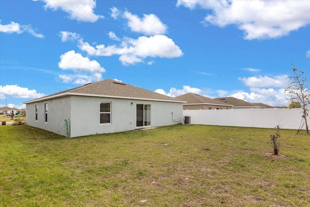 back of property featuring fence, a lawn, and stucco siding