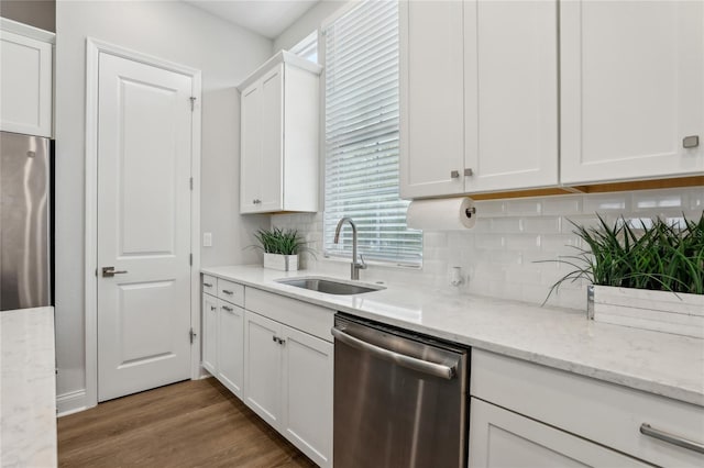 kitchen with a sink, backsplash, wood finished floors, stainless steel appliances, and white cabinets