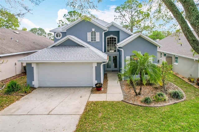 traditional-style house with concrete driveway, roof with shingles, an attached garage, a front lawn, and stucco siding