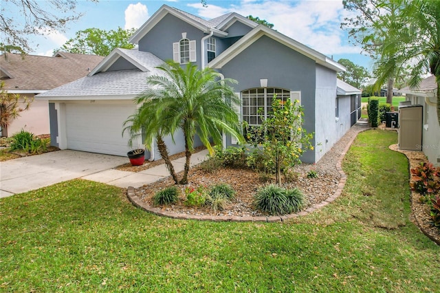 traditional-style house featuring a garage, a front yard, driveway, and stucco siding