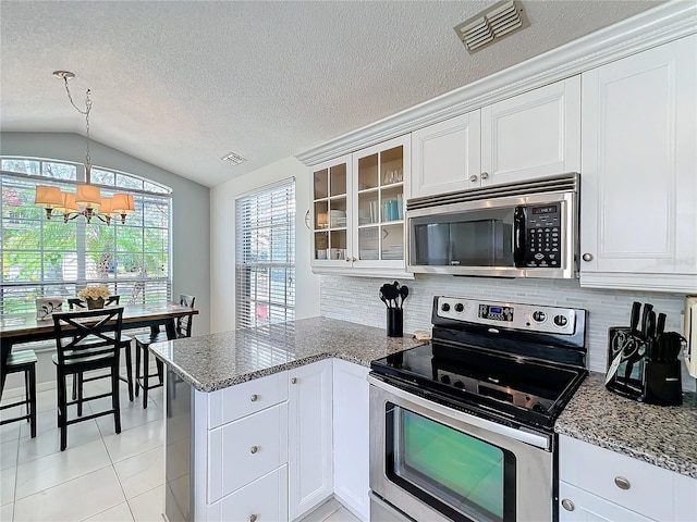 kitchen featuring a peninsula, appliances with stainless steel finishes, glass insert cabinets, and visible vents