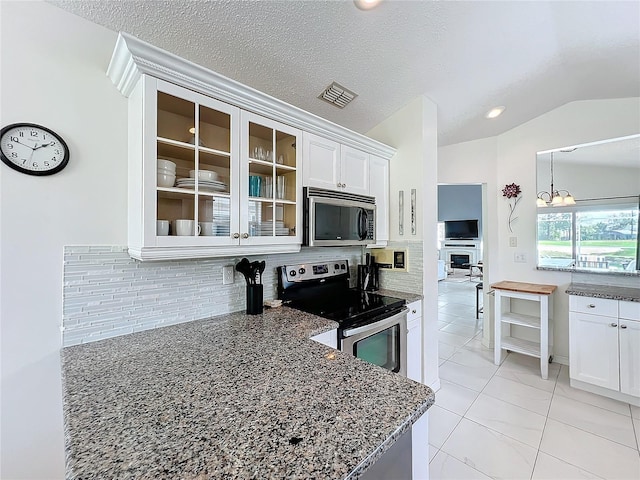 kitchen featuring stainless steel appliances, tasteful backsplash, glass insert cabinets, vaulted ceiling, and dark stone countertops