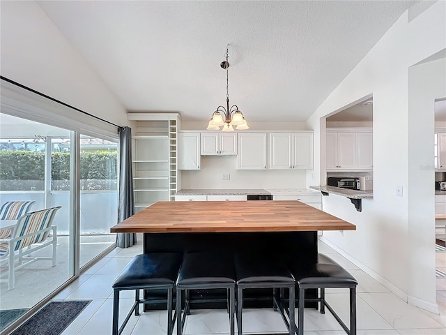 kitchen featuring lofted ceiling, butcher block countertops, a breakfast bar area, and a chandelier