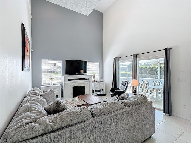 living room featuring a high end fireplace, plenty of natural light, a towering ceiling, and baseboards