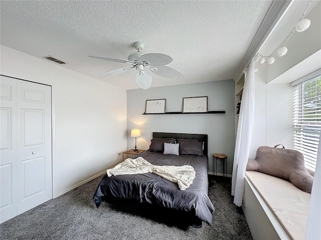 bedroom featuring carpet floors, a textured ceiling, visible vents, and a ceiling fan