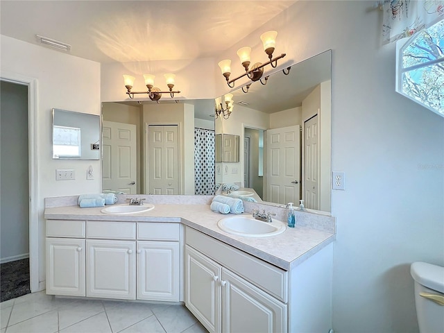 bathroom with a chandelier, toilet, a sink, and visible vents