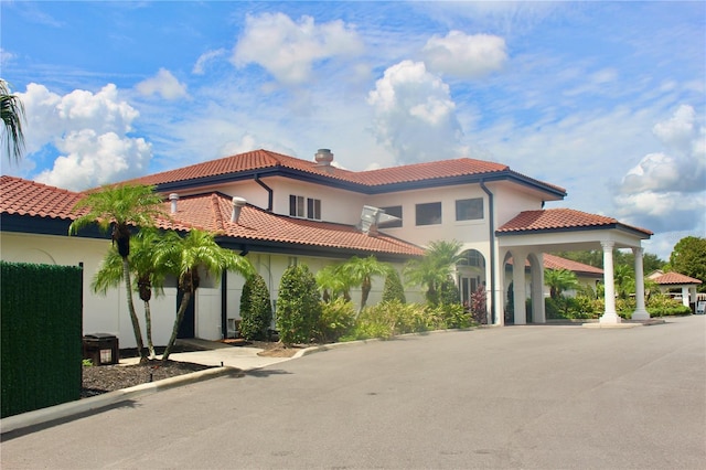 view of front facade with driveway, a chimney, a tiled roof, a gazebo, and stucco siding