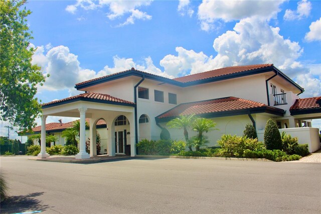 mediterranean / spanish-style house featuring a tiled roof, a balcony, and stucco siding