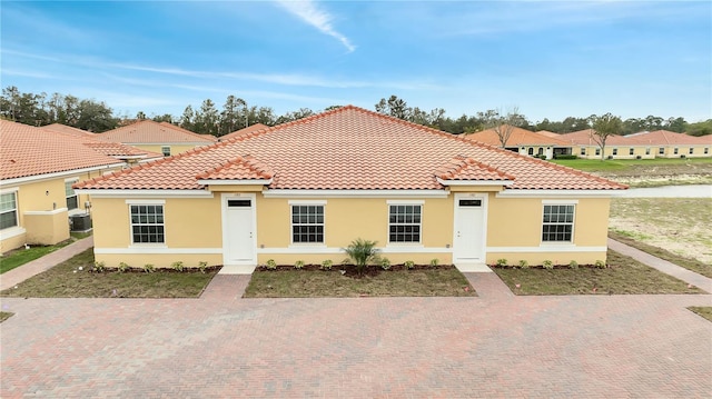 mediterranean / spanish-style house featuring central air condition unit, a tiled roof, and stucco siding