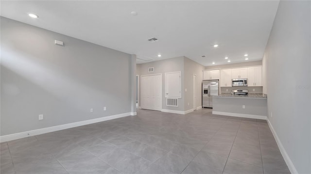 unfurnished living room featuring baseboards, visible vents, and recessed lighting