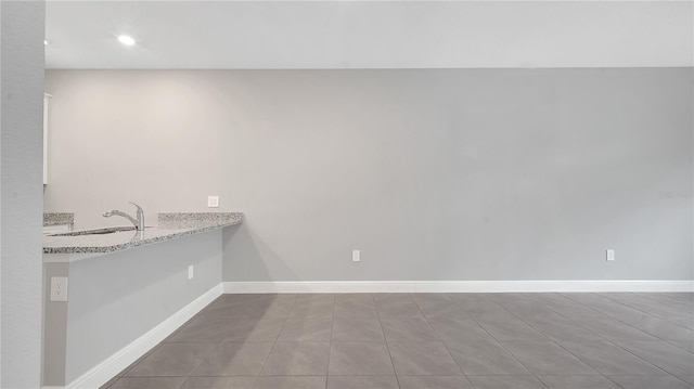 interior space featuring baseboards, light stone counters, a sink, and recessed lighting