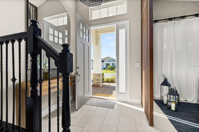 foyer entrance with tile patterned floors, stairway, and baseboards