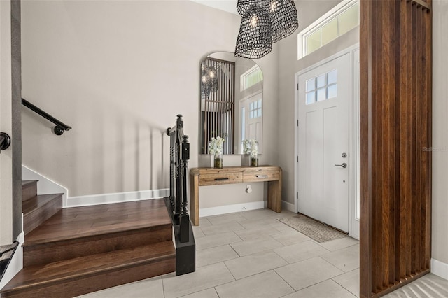 foyer featuring baseboards, stairs, and a towering ceiling