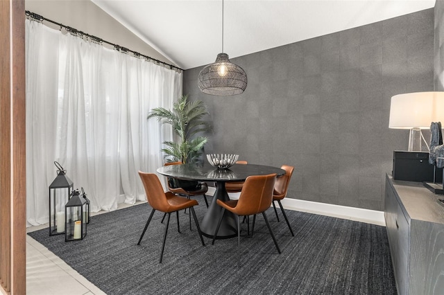 dining area featuring baseboards and lofted ceiling