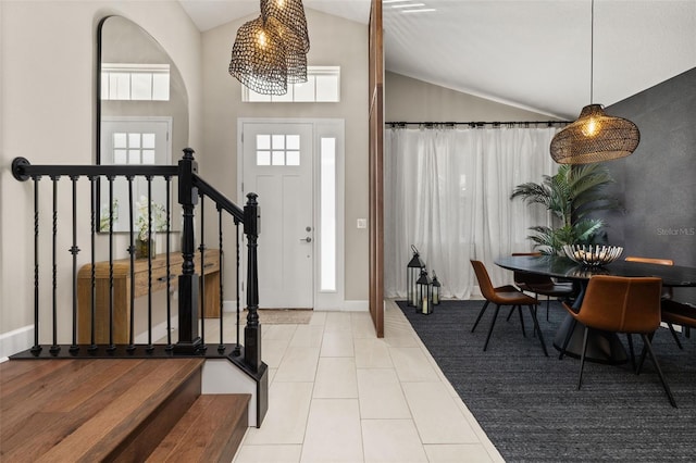 tiled entryway with baseboards, stairs, and lofted ceiling