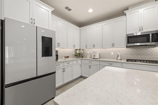 kitchen with white cabinets, light tile patterned flooring, visible vents, and stainless steel appliances