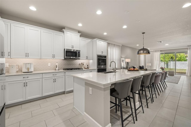 kitchen with a spacious island, light countertops, appliances with stainless steel finishes, white cabinetry, and tasteful backsplash