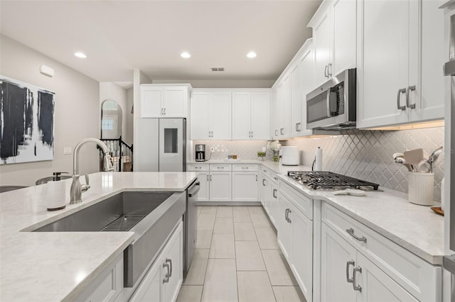 kitchen featuring visible vents, appliances with stainless steel finishes, white cabinetry, and a sink