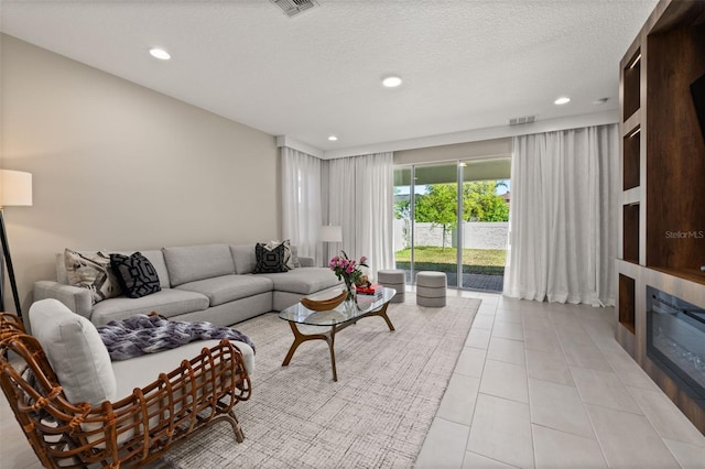 living area with light tile patterned floors, a glass covered fireplace, recessed lighting, and visible vents