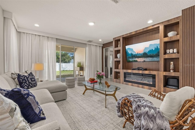 living area featuring a glass covered fireplace, built in features, recessed lighting, and a textured ceiling