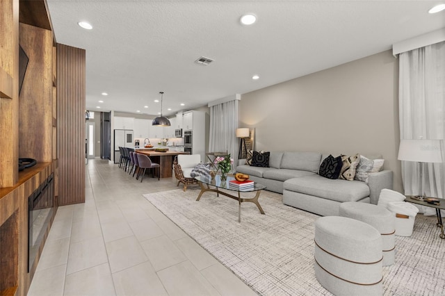 living room with light tile patterned flooring, recessed lighting, visible vents, and a textured ceiling