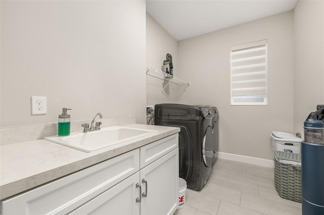 clothes washing area with light tile patterned floors, baseboards, separate washer and dryer, cabinet space, and a sink