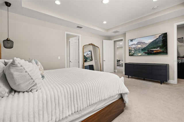 carpeted bedroom with a tray ceiling, recessed lighting, visible vents, and baseboards