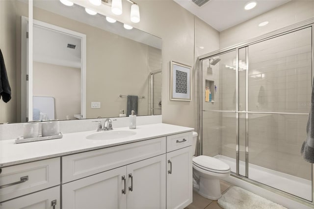 bathroom with tile patterned floors, visible vents, toilet, a stall shower, and vanity