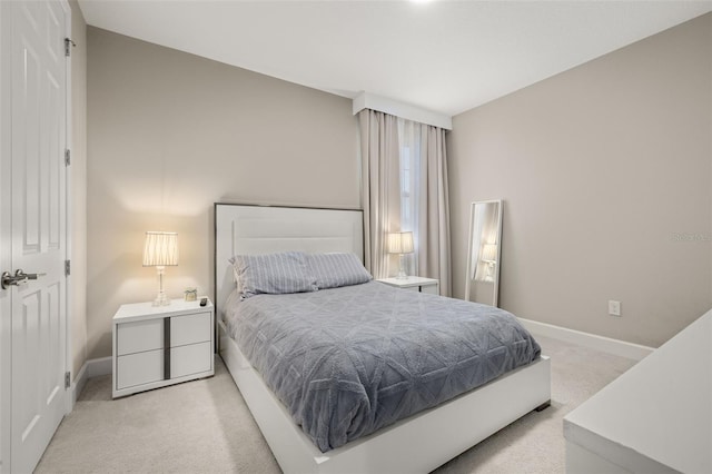 bedroom with light colored carpet and baseboards