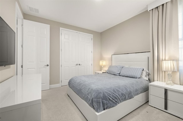 bedroom with a closet, visible vents, light colored carpet, and baseboards