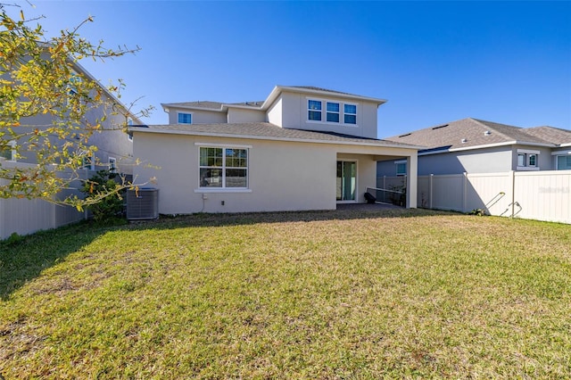 rear view of property with a yard, central AC unit, stucco siding, and fence