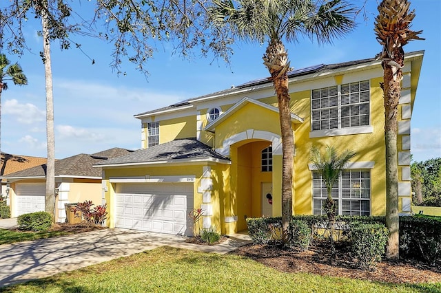 traditional-style home featuring a garage, concrete driveway, roof mounted solar panels, and stucco siding